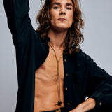 Model in black shirt wearing the Tie Me Up Black Tourmaline Necklace by Märta Larsson, a raw tourmaline lariat styled for modern power dressing.