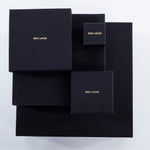 Luxury packaging for Märta Larsson jewelry, black boxes with gold branding designed for pyrite rings and crystal accessories.