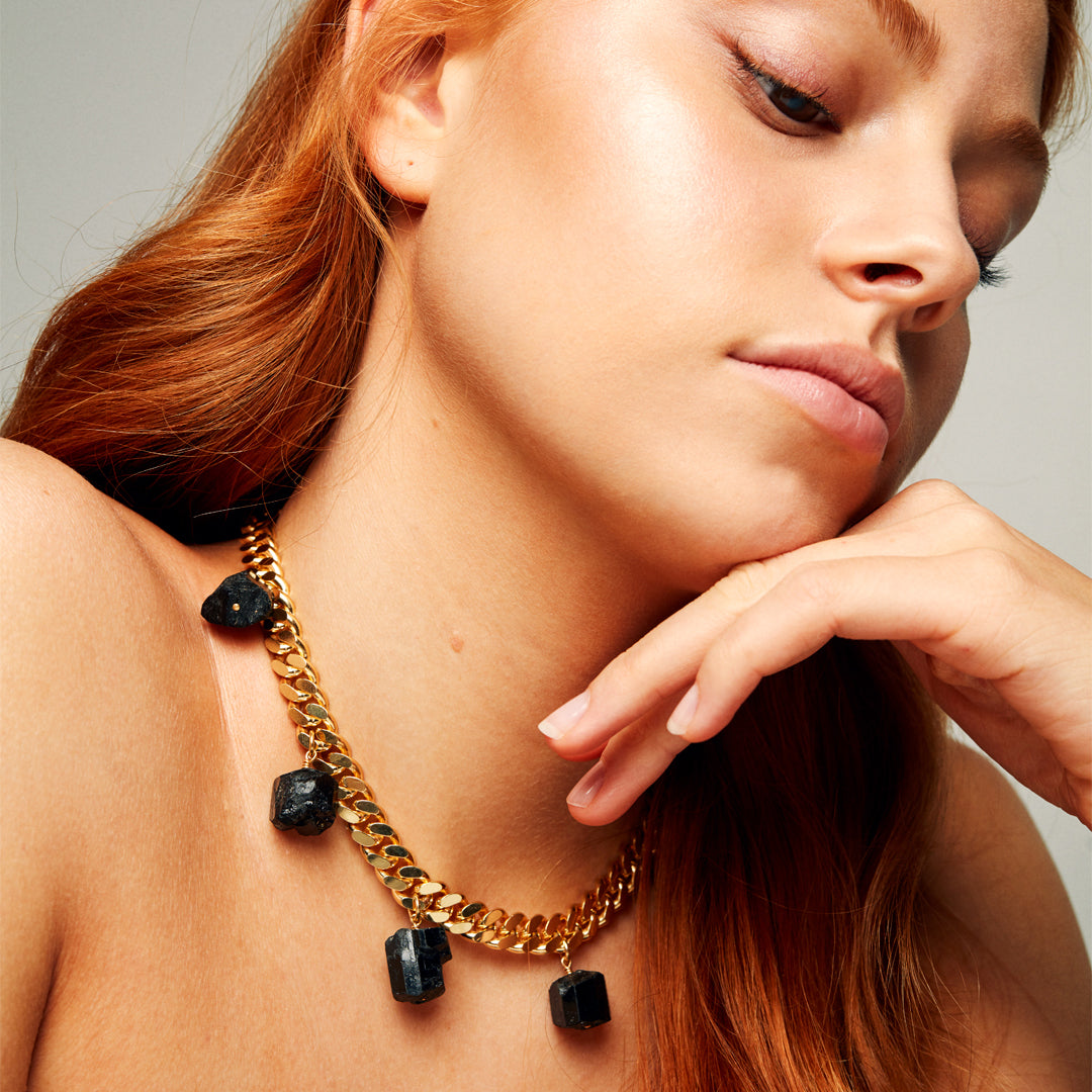 Model wearing the Collar Black Tourmaline Necklace by Märta Larsson with red hair and satin blouse, a raw tourmaline piece for modern luxury.