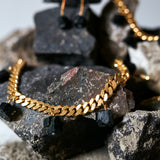 Collar Black Tourmaline Necklace by Märta Larsson on textured rocks, a gold-chain design with raw black tourmaline for bold natural luxury.