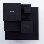 Luxury packaging for Märta Larsson jewelry, black boxes with gold branding designed for pyrite rings and crystal accessories.      