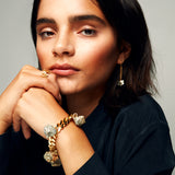  Portrait featuring brushed gold ring, chain bracelet and sculptural earring by Märta Larsson, styled with soft lighting and neutral tones.