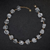 Not a Pearl Necklace Rough Quartz by Märta Larsson laid out on a black textured surface, featuring raw quartz stones on a gold chain.