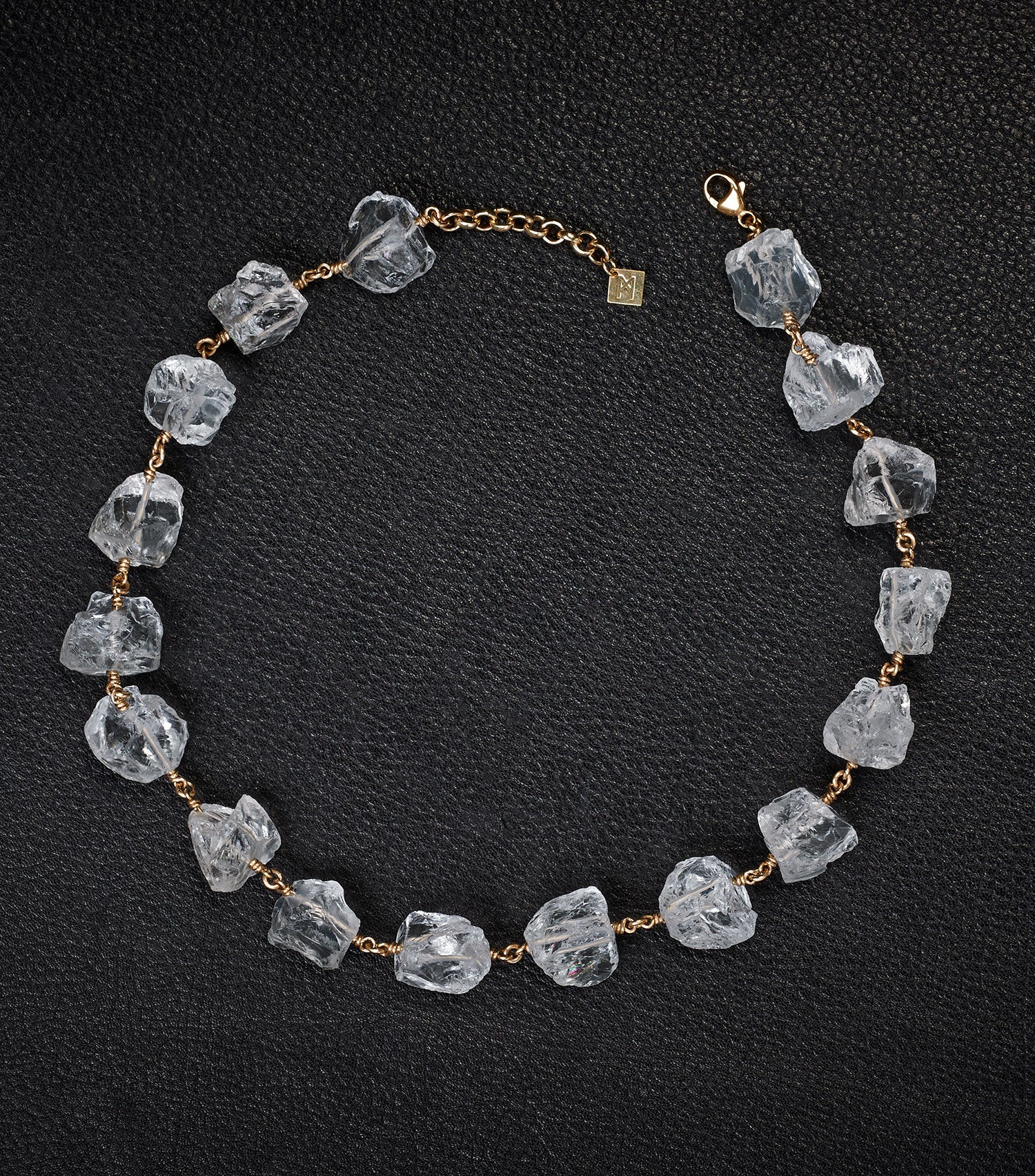 Not a Pearl Necklace Rough Quartz by Märta Larsson laid out on a black textured surface, featuring raw quartz stones on a gold chain.