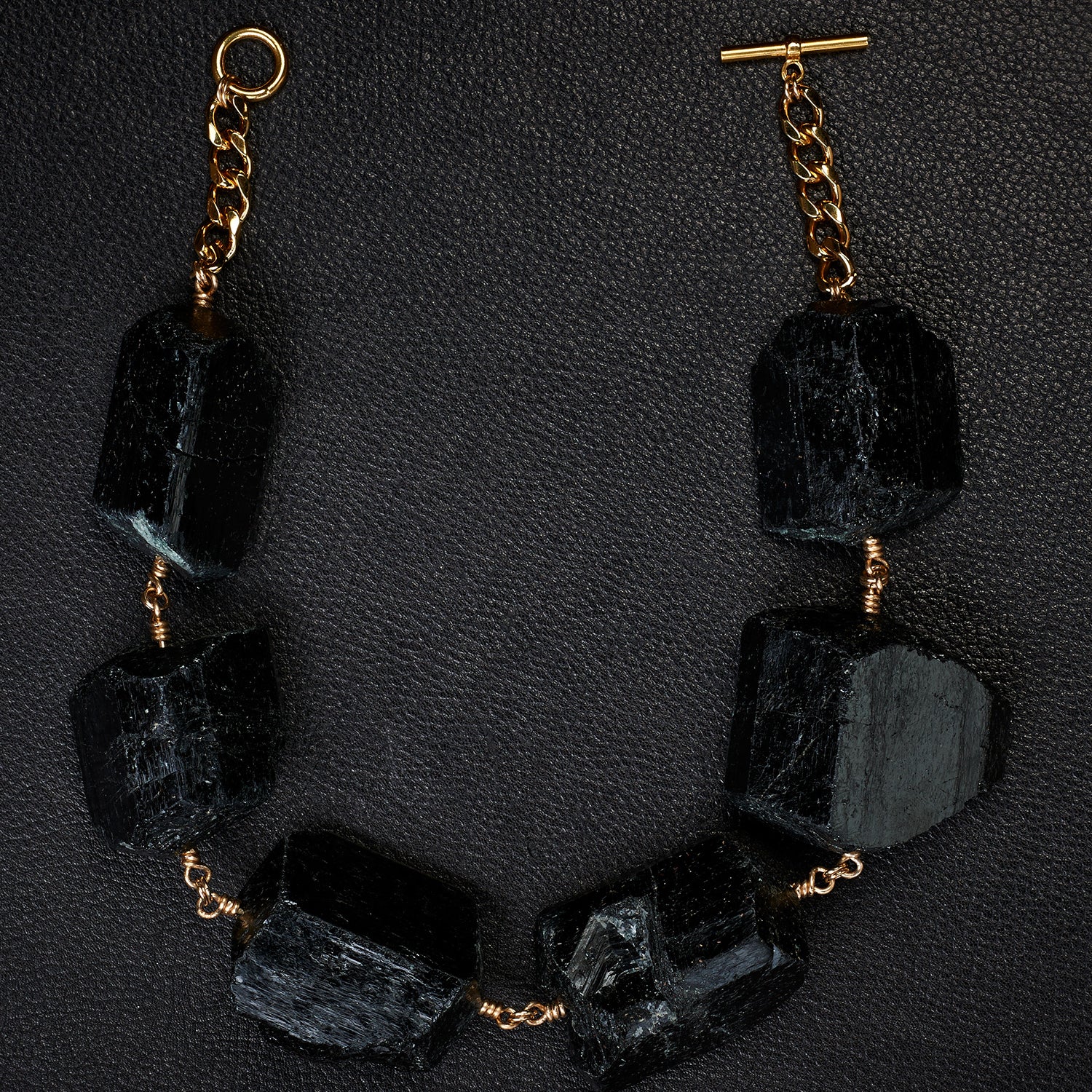 Not a Pearl Necklace XXL Black Tourmaline by Märta Larsson laid out on a black textured surface, featuring chunky raw tourmaline and a gold toggle clasp.