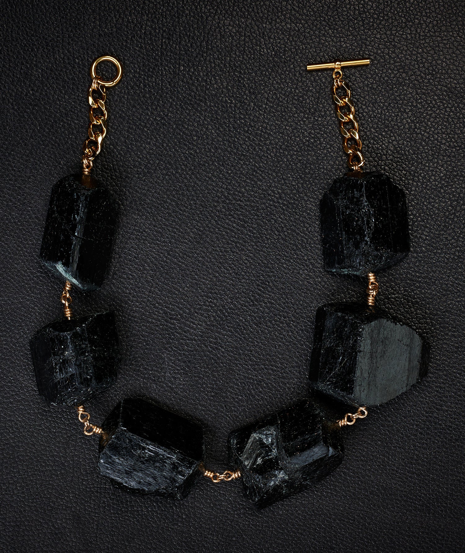 Not a Pearl Necklace XXL Black Tourmaline by Märta Larsson laid out on a black textured surface, featuring chunky raw tourmaline and a gold toggle clasp.