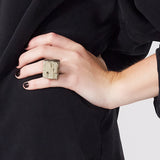 Model in black outfit wearing Roxx Pyrite Cube Ring by Märta Larsson on middle finger. Pyrite crystal ring styled with black nails — bold and confident fashion look.
