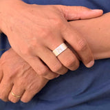 Two hands wearing silver and gold rings, one engraved with Roman numeral X — a symbolic and intimate composition.
