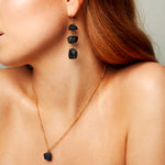 Model wearing The Raw One Black Tourmaline Necklace by Märta Larsson with matching earrings, a raw black crystal piece styled with neutral tones for day-to-night looks.