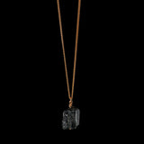 The Raw One Black Tourmaline Necklace by Märta Larsson with a raw crystal pendant on a gold-vermeil chain, a handcrafted piece with natural ridges and bold texture.