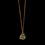 Gold vermeil necklace with raw pyrite crystal by Märta Larsson against a black background — refined shine meets raw mineral energy.