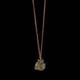 Gold vermeil necklace with raw pyrite crystal by Märta Larsson against a black background — refined shine meets raw mineral energy.