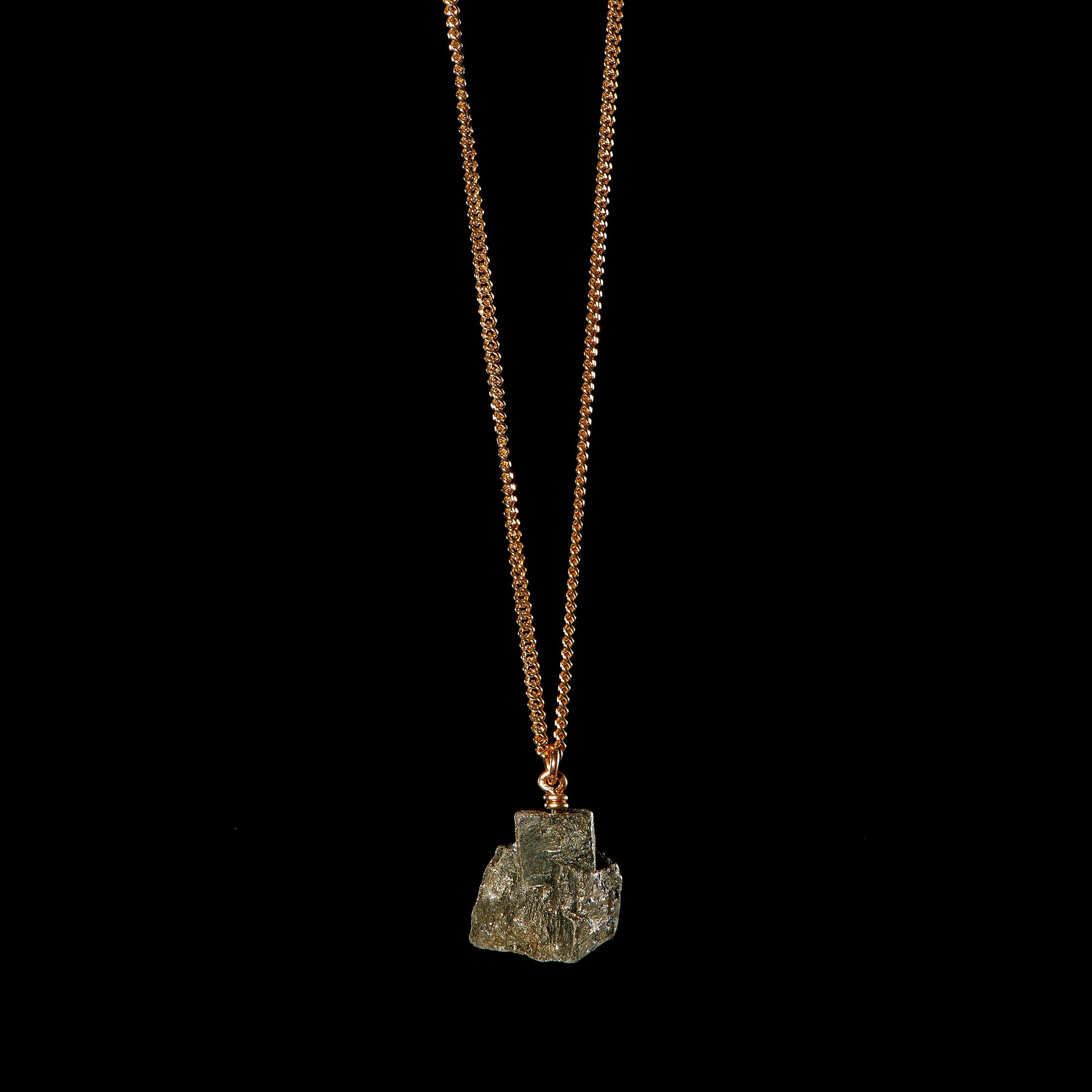 Gold vermeil necklace with raw pyrite crystal by Märta Larsson against a black background — refined shine meets raw mineral energy.