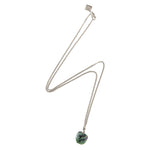 Silver chain necklace with a raw ruby zoisite stone, arranged in a lightning-like shape on a white background.