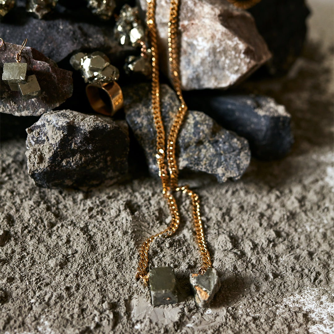 Jewelry styled on volcanic rocks featuring the Tie Me Up Pyrite Necklace by Märta Larsson with matching ring and earrings, raw and ruggedly elegant.