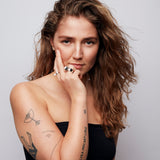 Brown-haired model wearing two Billie Ring Recycled Silver by Märta Larsson on index and ring fingers, showcasing versatile handcrafted silver design against a grey background.