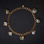 Collar Calcite Pyrite Necklace by Märta Larsson laid out on a black surface, featuring raw calcite-pyrite stones on a gold collar chain.