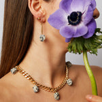 Model wearing the Collar Dalmatian Necklace by Märta Larsson with a matching earring and a purple flower, styled with expressive everyday elegance.