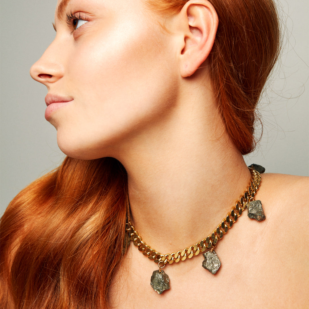Model wearing the Collar Pyrite Necklace by Märta Larsson with red hair and minimalist styling, a raw pyrite statement piece for confident elegance.
