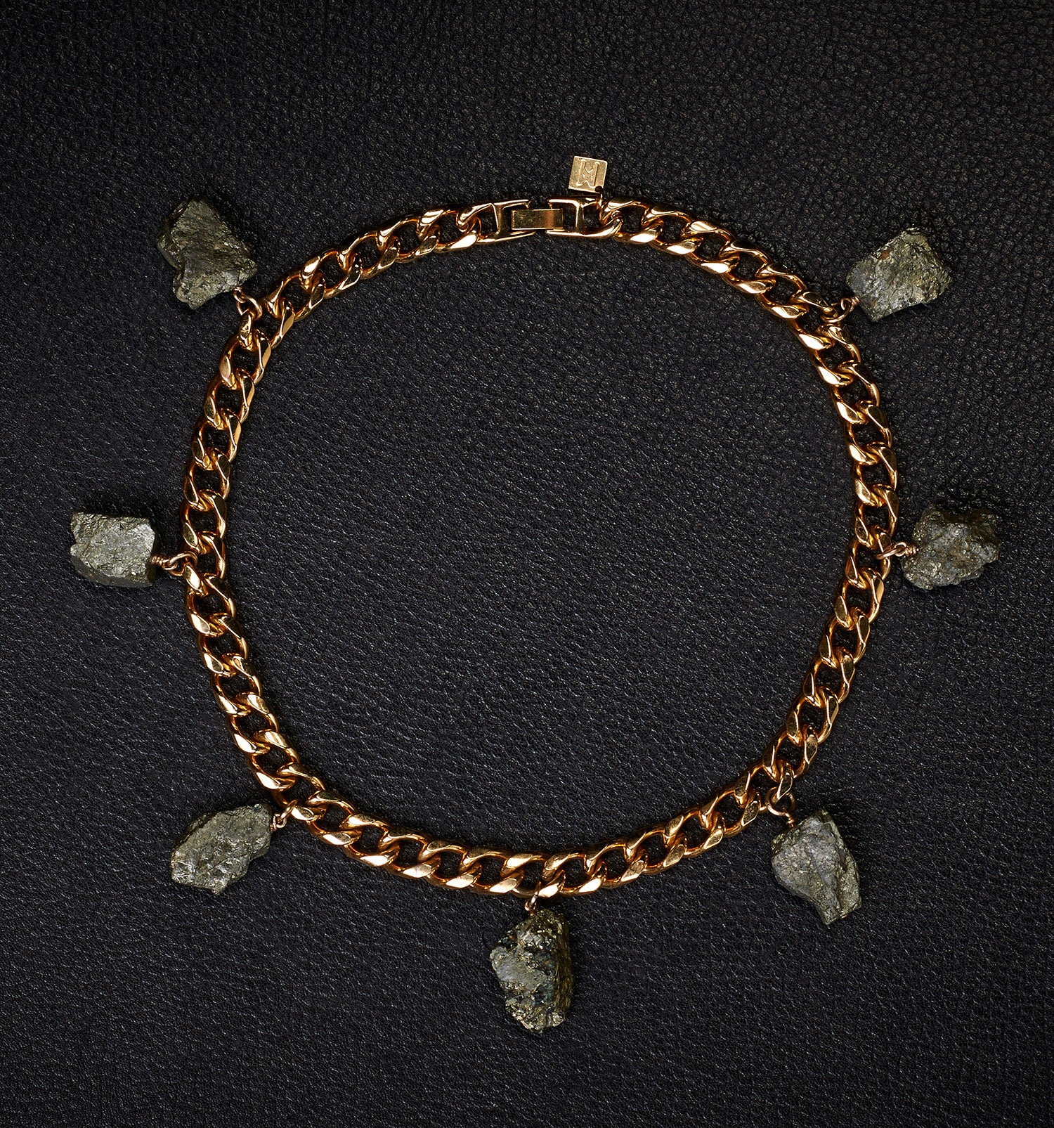 Collar Pyrite Necklace by Märta Larsson laid out on black textured surface. Gold collar necklace with raw pyrite stones — edgy, refined, and handcrafted.
