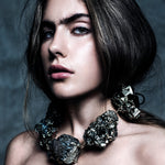 Model wearing the Not a Pearl Necklace XXL Art Edition Pyrite Crystal by Märta Larsson with voluminous hair and a textured backdrop, styled for confident artistic elegance.