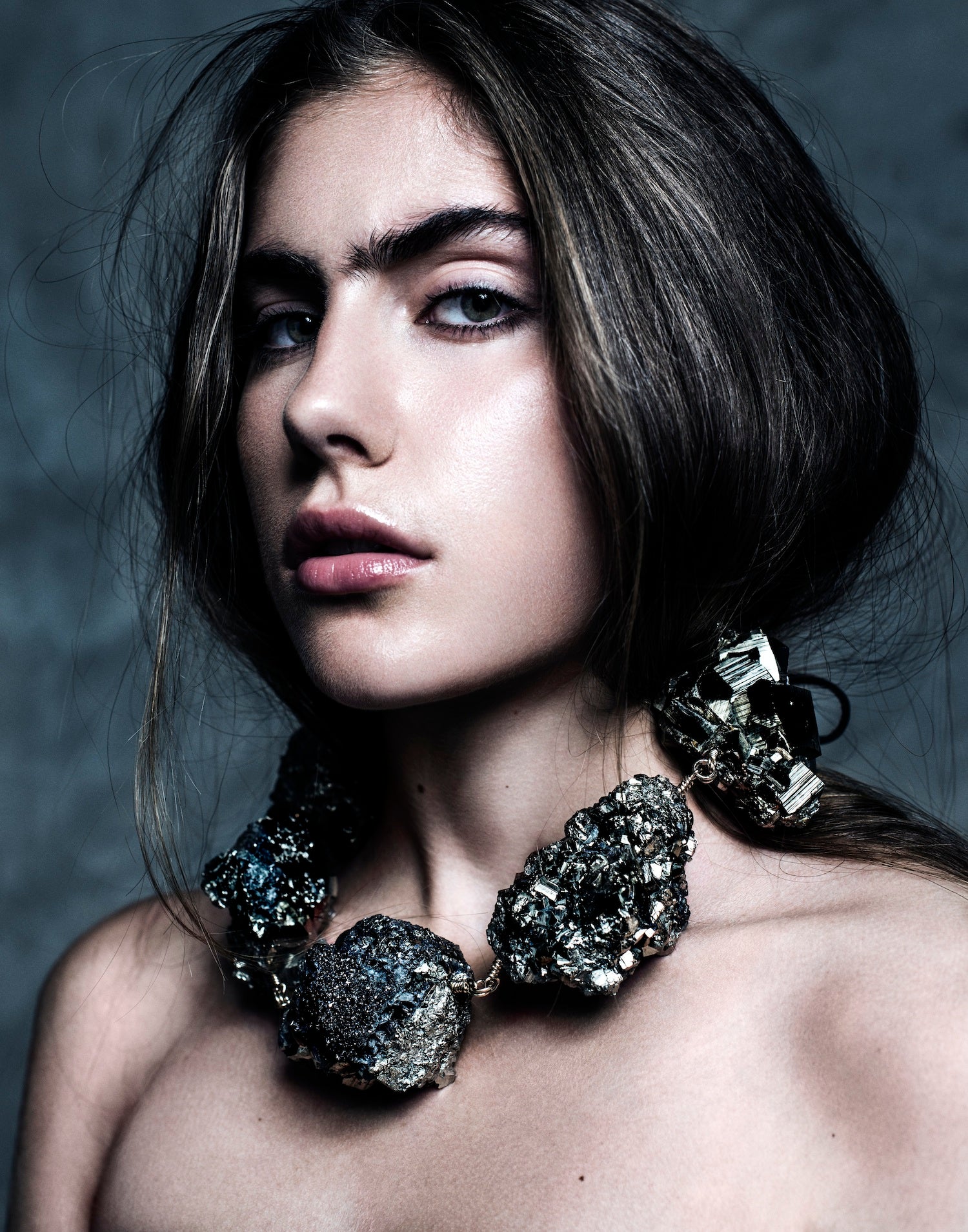 Model wearing the Not a Pearl Necklace XXL Art Edition Pyrite Crystal by Märta Larsson with voluminous hair and a textured backdrop, styled for confident artistic elegance.