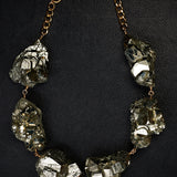 Not a Pearl Necklace XXL Art Edition Pyrite Crystal by Märta Larsson laid out on a black textured surface, featuring raw pyrite crystals on a gold chain.