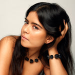 Model wearing the Not a Pearl Necklace Black Tourmaline by Märta Larsson with a faceted black bracelet and gold earrings, styled for bold radiant fashion.