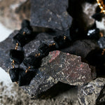Not a Pearl Necklace Black Tourmaline by Märta Larsson styled among rugged black stones with a gold chain, featuring raw tourmaline for earthy power.