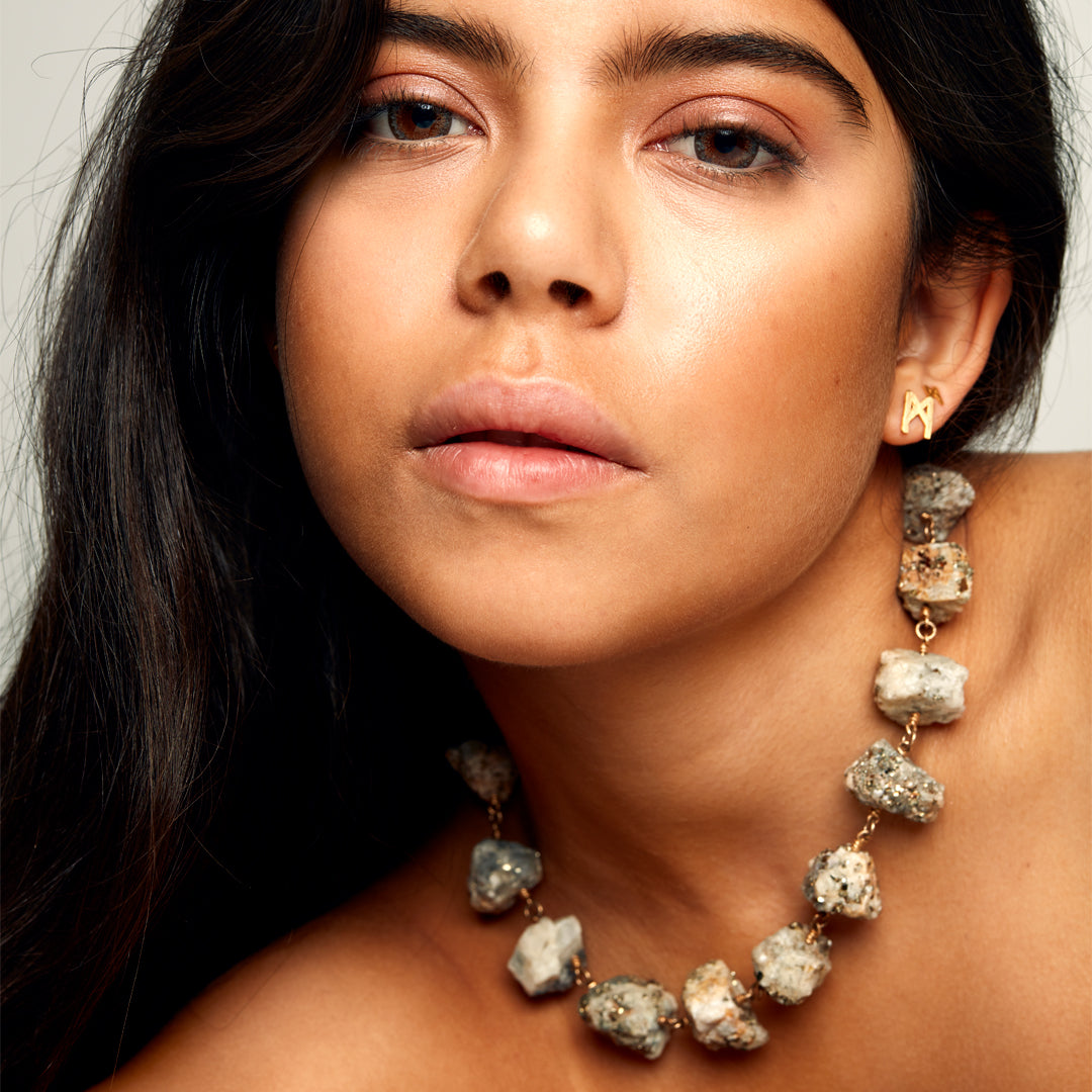Close-up of the Not a Pearl Necklace Calcite Pyrite by Märta Larsson with a matching gold stud earring, featuring chunky raw crystal texture.