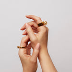 Two hands raised in the air, one wearing The Power Ring by Märta Larsson in gold vermeil on the index finger, featuring a bold raw crystal design.