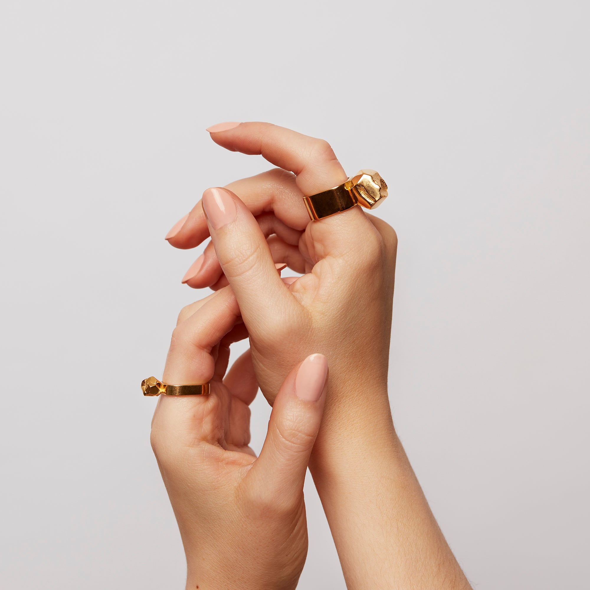 Two hands raised in the air, one wearing The Power Ring by Märta Larsson in gold vermeil on the index finger, featuring a bold raw crystal design.