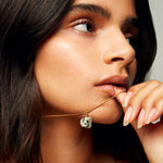 Model holding The Raw One Dalmatian Necklace by Märta Larsson with bear-shaped pendant, a playful raw dalmatian stone piece on gold vermeil chain.