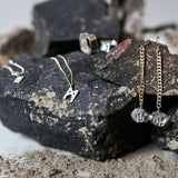 Jewelry styled on textured rocks featuring Signature Necklace Brushed Silver by Märta Larsson, a minimalist brushed-silver M charm necklace.