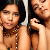 Close-up of two models wearing the Gold Chain Belt & Necklace by Märta Larsson, a bold polished gold chain styled with earrings and a bracelet.