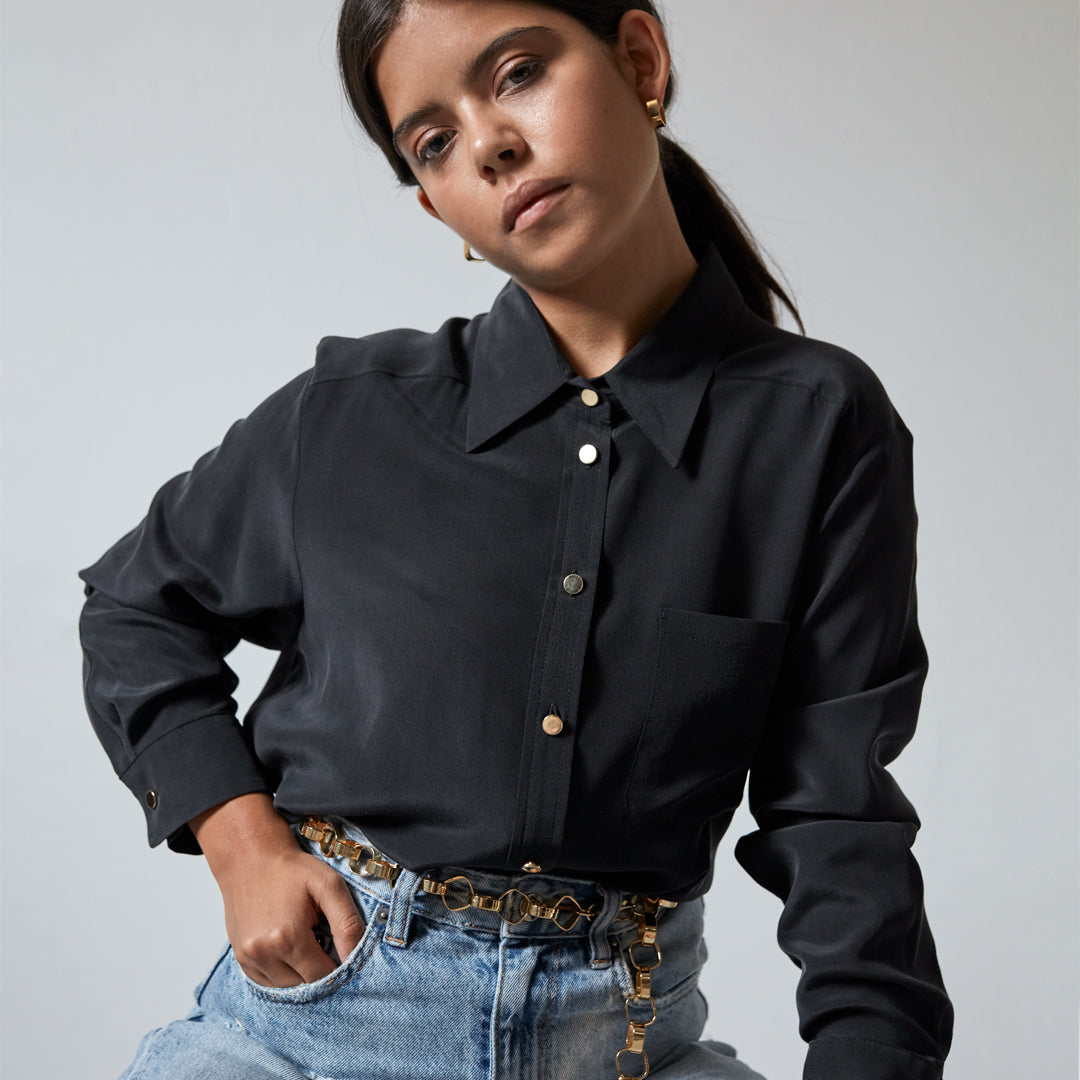 Model in black shirt and jeans wearing the Gold Chain Belt & Necklace by Märta Larsson, a chunky gold chain styled for casual elegance and edge.
