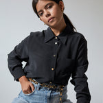 Model in black shirt and jeans wearing the Gold Chain Belt & Necklace by Märta Larsson, a chunky gold chain styled for casual elegance and edge.