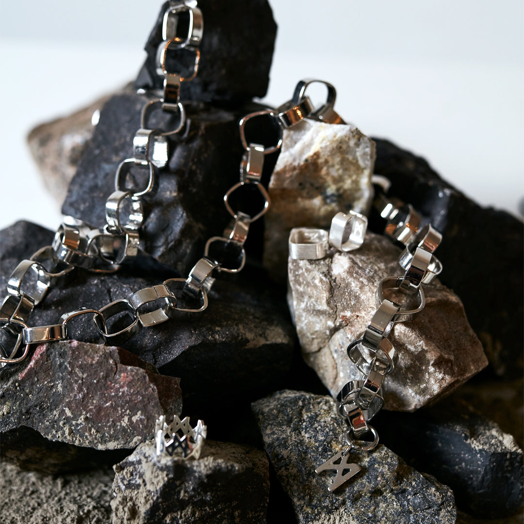 Signature Silver Chain Belt & Necklace by Märta Larsson on textured rocks, a polished geometric-link silver chain blending elegant and industrial style.