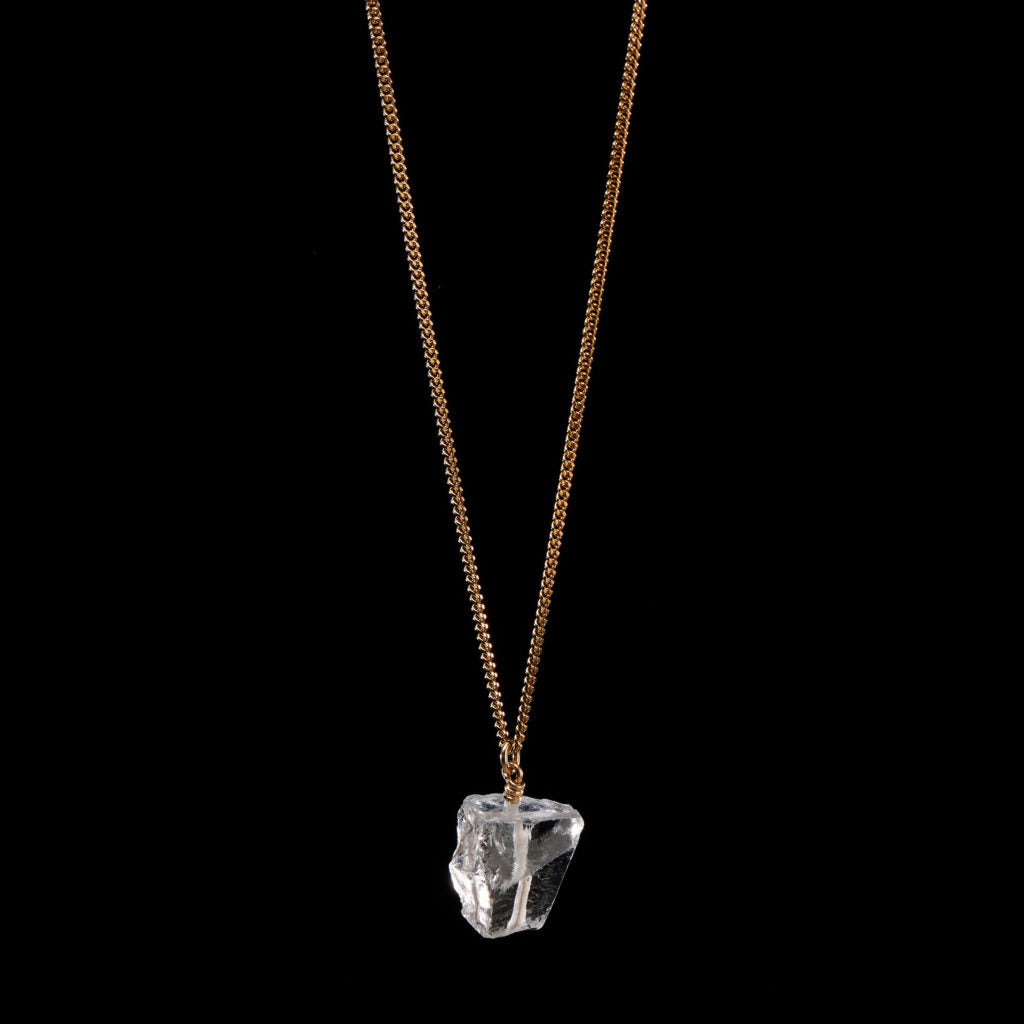 The Raw One Rough Quartz Necklace by Märta Larsson on black background, a gold-vermeil chain with raw clear quartz for bold frozen-light contrast.