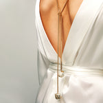 Back view of model in white satin dress wearing the Tie Me Up Calcite Pyrite Necklace, a gold lariat with raw quartz down the spine.