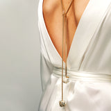 Back view of model in white satin dress wearing the Tie Me Up Calcite Pyrite Necklace, a gold lariat with raw quartz down the spine.